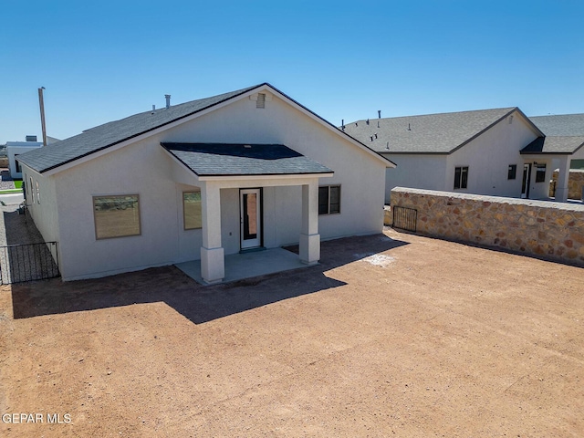 back of property with stucco siding, roof with shingles, a patio, and a fenced backyard