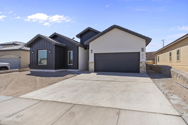 813 Durham Way, Horizon City, TX 79928 - view of front of house featuring board and batten siding, an attached garage, stone siding, and driveway