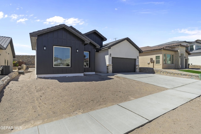 813 Durham Way, Horizon City, TX 79928 - view of front of home featuring central AC unit, stone siding, concrete driveway, a garage, and board and batten siding