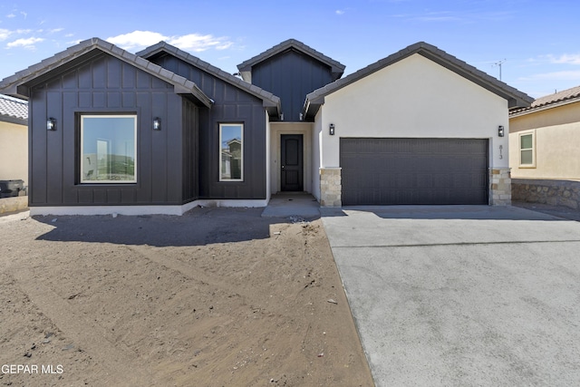 813 Durham Way, Horizon City, TX 79928 - view of front of house featuring board and batten siding, an attached garage, driveway, and stone siding