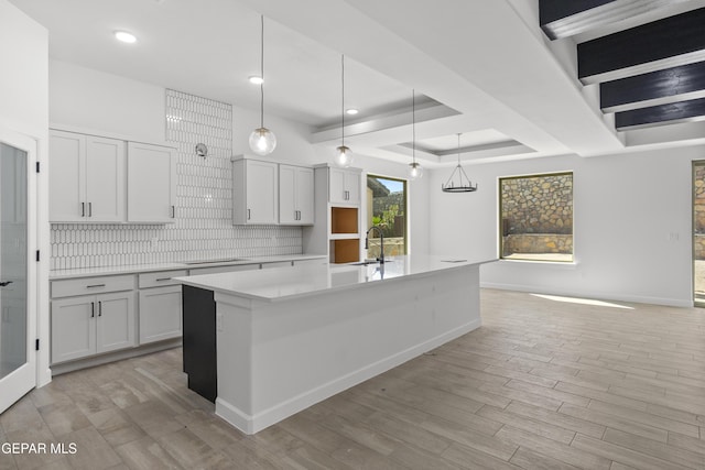 813 Durham Way, Horizon City, TX 79928 - kitchen featuring an island with sink, light countertops, light wood-style flooring, backsplash, and black cooktop