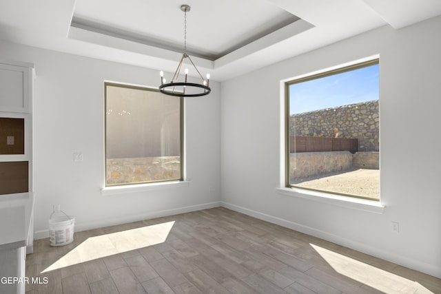 813 Durham Way, Horizon City, TX 79928 - unfurnished dining area with baseboards, a notable chandelier, wood finished floors, and a raised ceiling