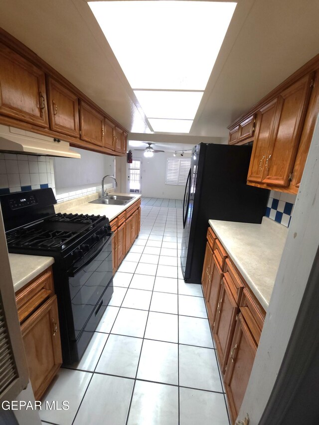 10850 Valle Grande Ct, El Paso, TX 79935 - kitchen with black appliances, a sink, under cabinet range hood, brown cabinets, and tasteful backsplash
