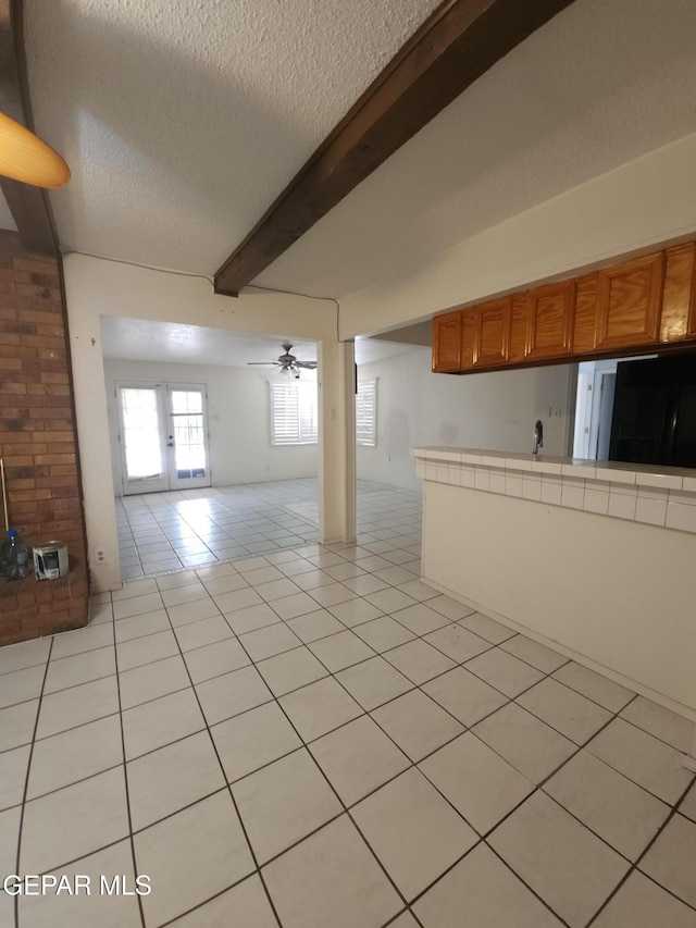10850 Valle Grande Ct, El Paso, TX 79935 - unfurnished living room featuring light tile patterned flooring, beam ceiling, a textured ceiling, french doors, and ceiling fan