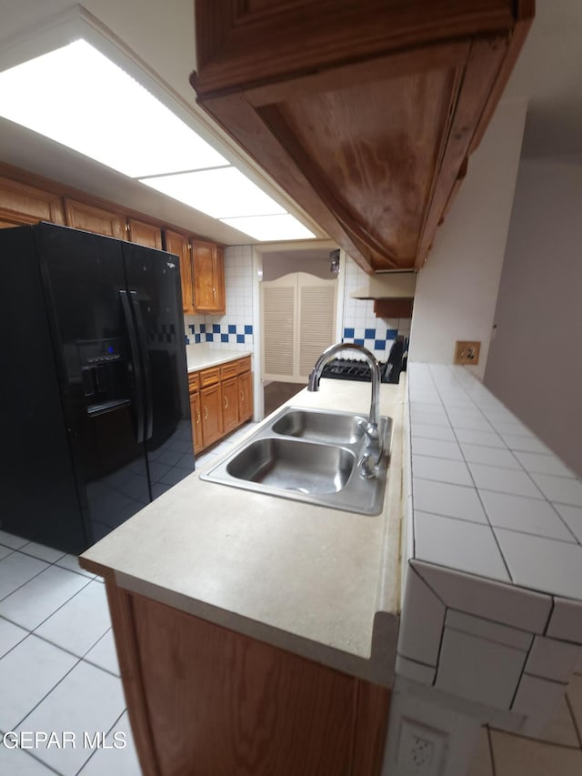 10850 Valle Grande Ct, El Paso, TX 79935 - kitchen with black refrigerator with ice dispenser, a sink, brown cabinets, a peninsula, and light countertops