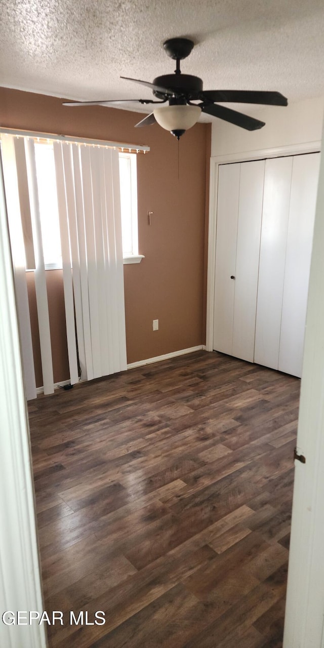 10850 Valle Grande Ct, El Paso, TX 79935 - unfurnished bedroom with dark wood-style floors, a textured ceiling, ceiling fan, baseboards, and a closet