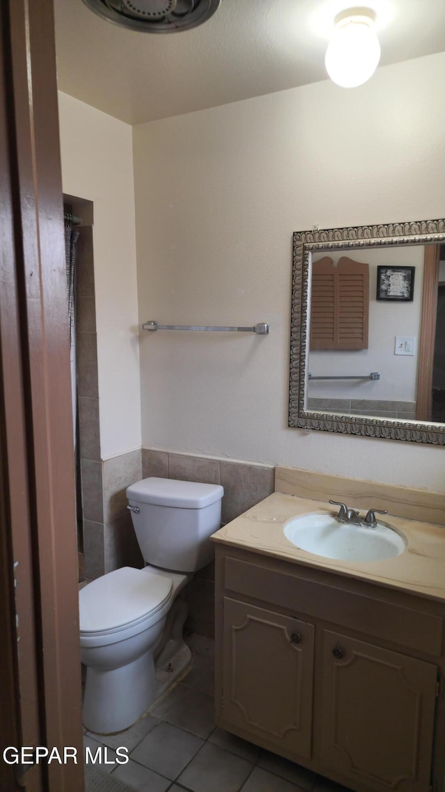 10850 Valle Grande Ct, El Paso, TX 79935 - full bath with tile walls, tile patterned floors, vanity, toilet, and a wainscoted wall