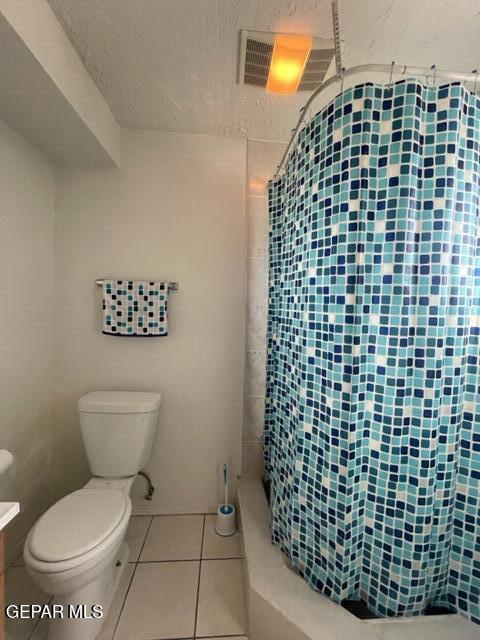 10850 Valle Grande Ct, El Paso, TX 79935 - bathroom with toilet, tiled shower, tile patterned flooring, and a textured ceiling