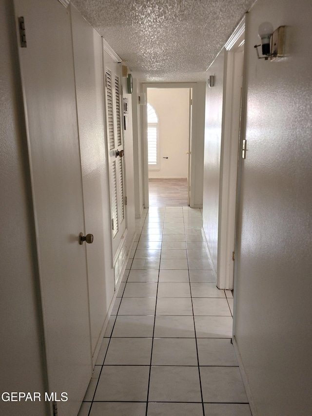 10850 Valle Grande Ct, El Paso, TX 79935 - corridor featuring light tile patterned flooring, a textured ceiling, and baseboards