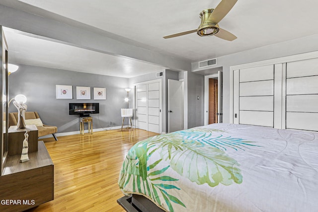 701 La Cruz Dr, El Paso, TX 79902 - bedroom featuring wood finished floors, baseboards, a glass covered fireplace, and visible vents