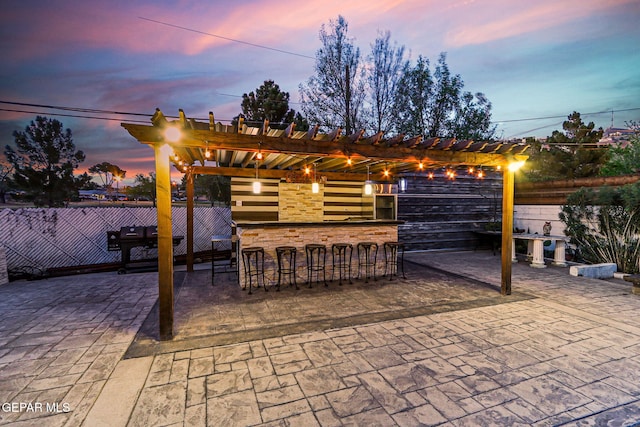 701 La Cruz Dr, El Paso, TX 79902 - patio terrace at dusk featuring a pergola, outdoor dry bar, and fence