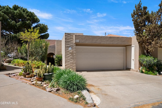 adobe home with a garage, stucco siding, and concrete driveway