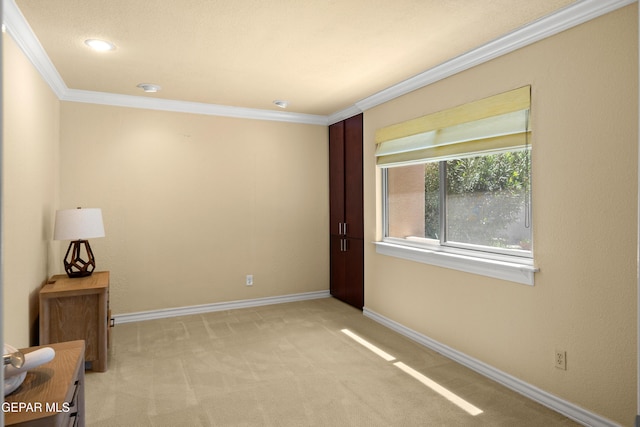 spare room with crown molding, light colored carpet, and baseboards