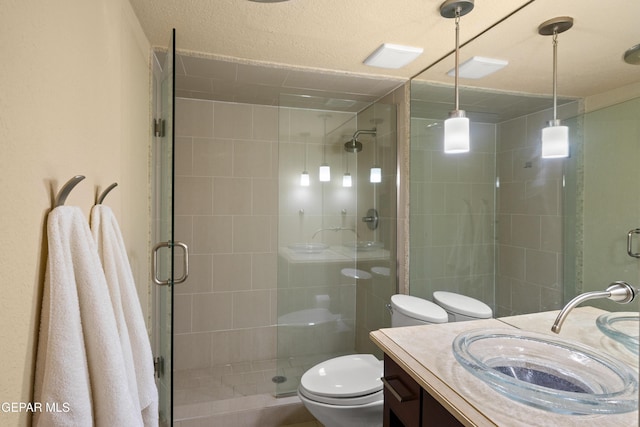 bathroom featuring toilet, a stall shower, and vanity
