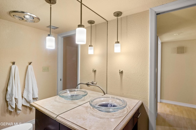 bathroom with visible vents, baseboards, vanity, and wood finished floors