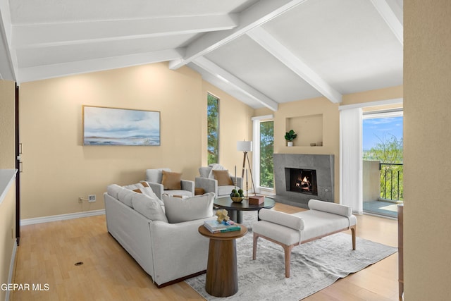 living area featuring light wood-type flooring, vaulted ceiling with beams, a tile fireplace, and baseboards