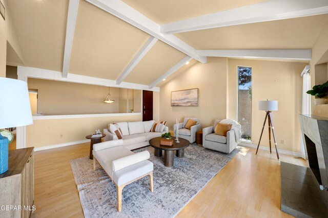 living area featuring a premium fireplace, lofted ceiling with beams, baseboards, and wood finished floors