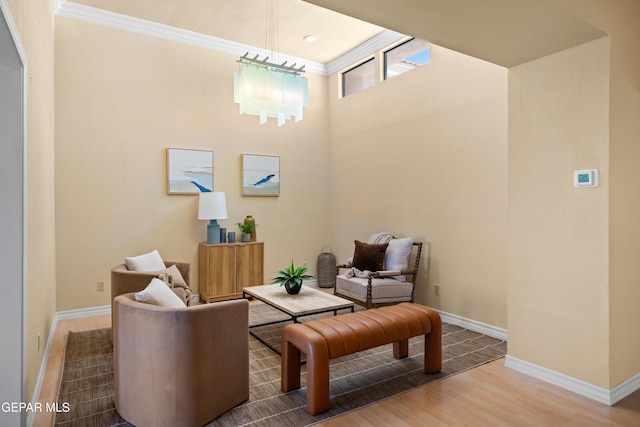 sitting room featuring baseboards, crown molding, and wood finished floors