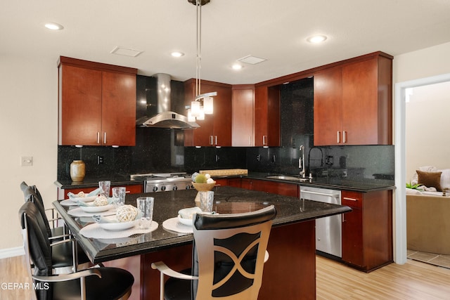 kitchen with tasteful backsplash, wall chimney exhaust hood, a sink, light wood-style floors, and stainless steel dishwasher