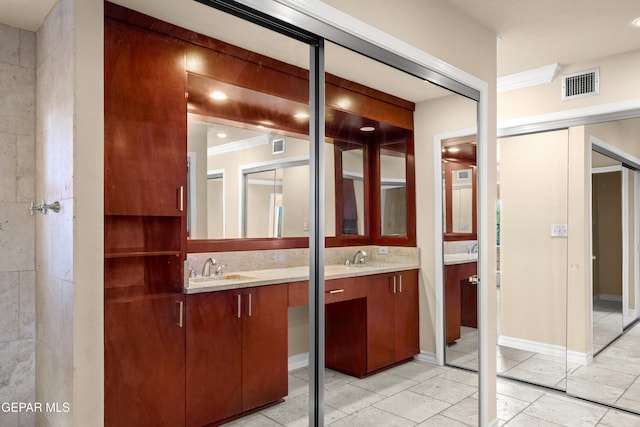 full bath with crown molding, visible vents, two vanities, and a sink