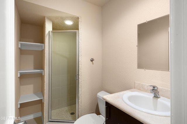 full bath featuring a shower stall, vanity, a textured wall, and toilet