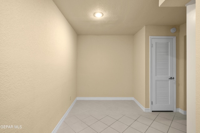 unfurnished room with light tile patterned floors, baseboards, and a textured ceiling