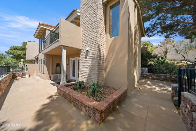exterior space featuring fence, a patio, stucco siding, and a balcony