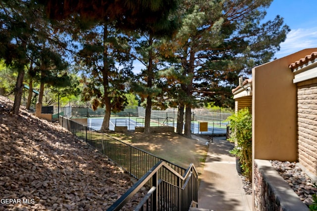 view of yard featuring a tennis court and fence