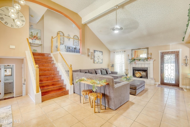 tiled living room featuring stairs, baseboards, a tiled fireplace, a textured ceiling, and high vaulted ceiling