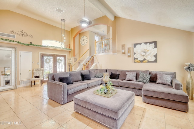 tiled living area with stairway, a textured ceiling, arched walkways, french doors, and visible vents