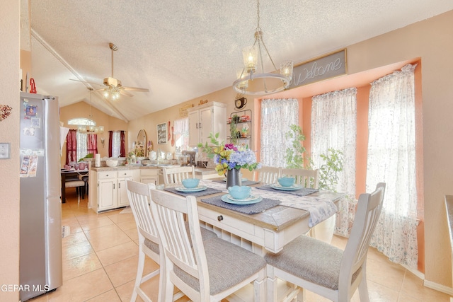 dining room featuring ceiling fan with notable chandelier, vaulted ceiling, a textured ceiling, and light tile patterned floors