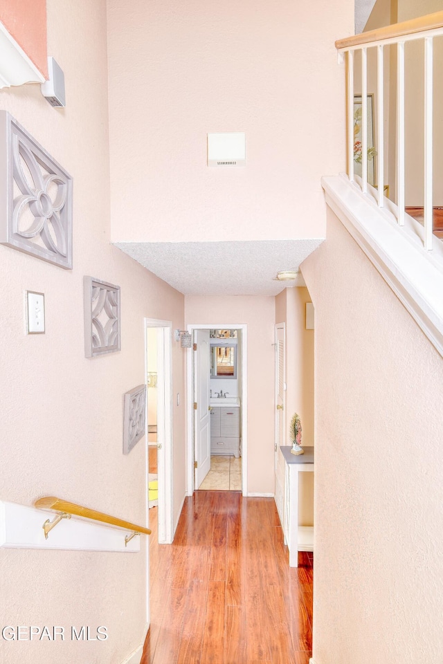 hallway featuring baseboards, wood finished floors, and a sink