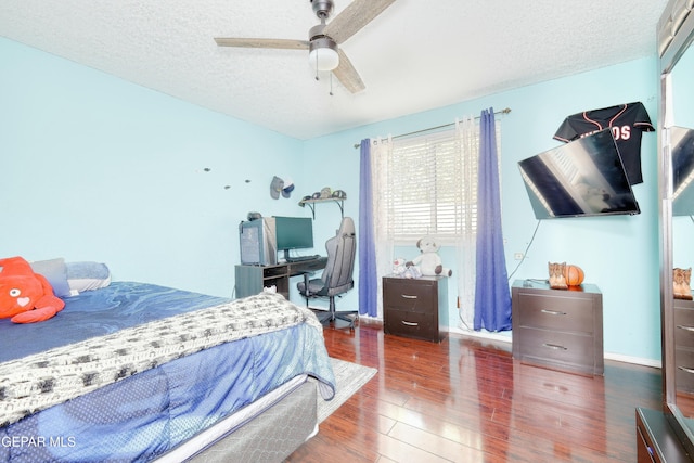 bedroom with baseboards, a ceiling fan, wood finished floors, and a textured ceiling
