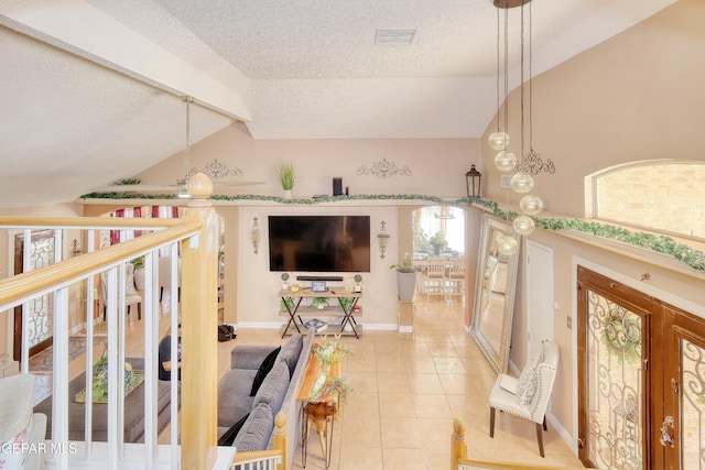 living area with a textured ceiling, light tile patterned flooring, vaulted ceiling, visible vents, and baseboards