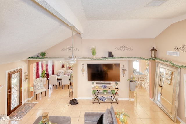 living area featuring a textured ceiling, visible vents, lofted ceiling with beams, and light tile patterned floors