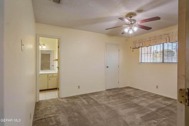 10632 Park View Cir, El Paso, TX 79935 - unfurnished bedroom with baseboards, ceiling fan, a textured ceiling, ensuite bath, and carpet flooring