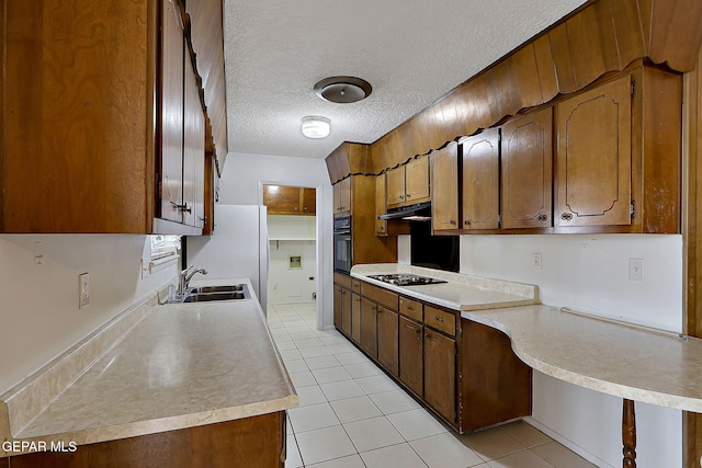 kitchen with a sink, light countertops, stovetop, and black oven