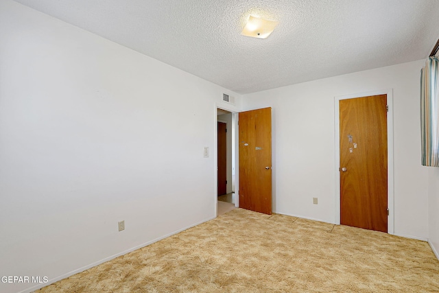 carpeted empty room with a textured ceiling and visible vents