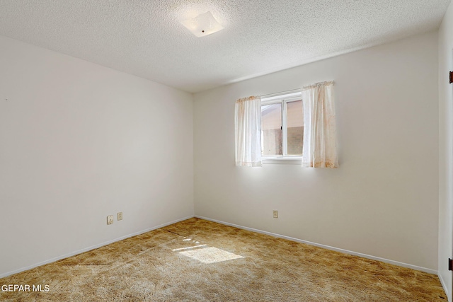 empty room with carpet flooring, a textured ceiling, and baseboards