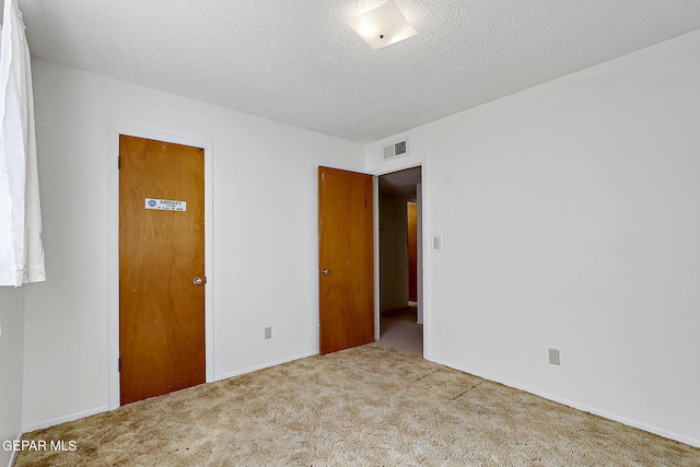 carpeted spare room featuring visible vents and a textured ceiling