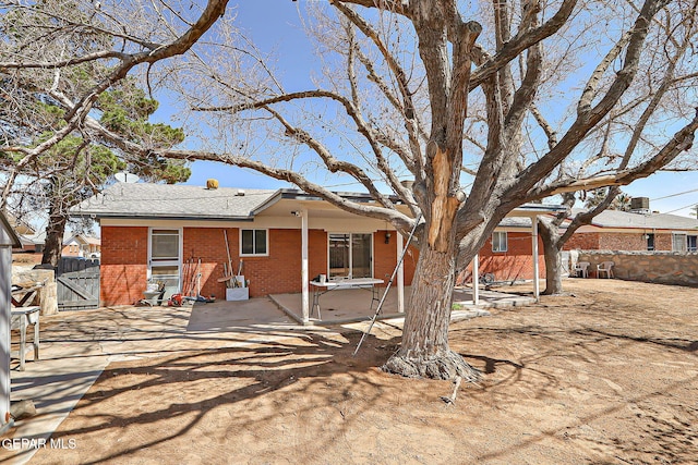 back of property featuring brick siding, fence, a gate, and a patio area