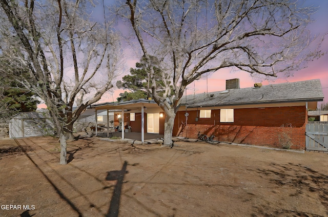 back of property featuring a patio area, fence, brick siding, and an outbuilding