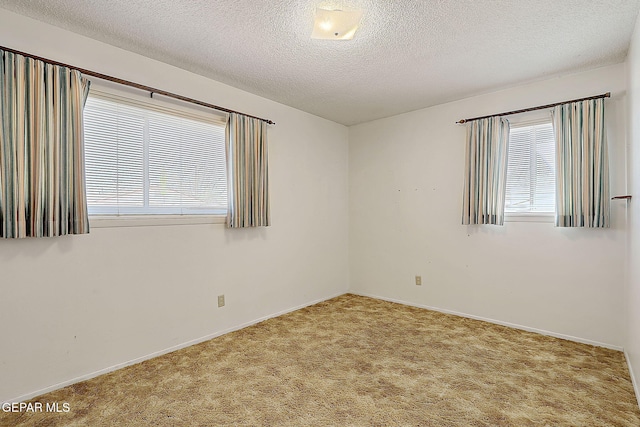 empty room featuring carpet flooring, a textured ceiling, and baseboards