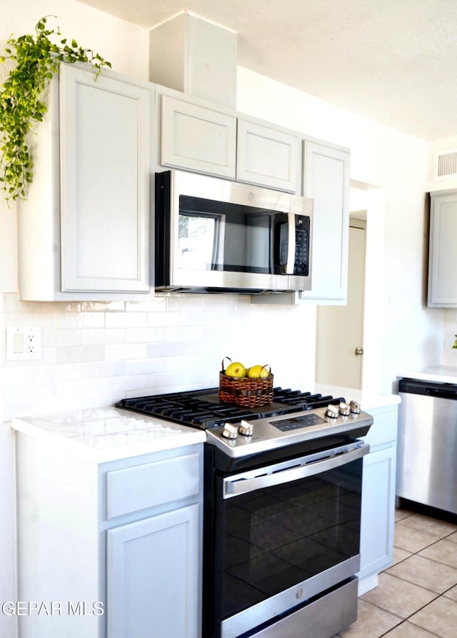 kitchen featuring appliances with stainless steel finishes, light tile patterned flooring, backsplash, and visible vents