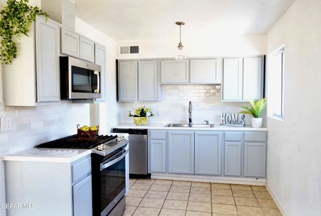kitchen with light countertops, backsplash, visible vents, appliances with stainless steel finishes, and a sink