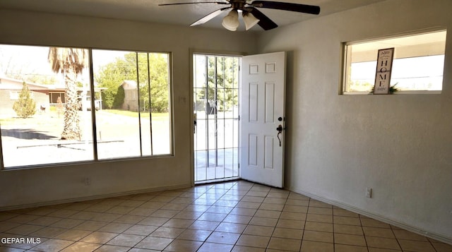 entryway featuring light tile patterned flooring, baseboards, a ceiling fan, and a wealth of natural light