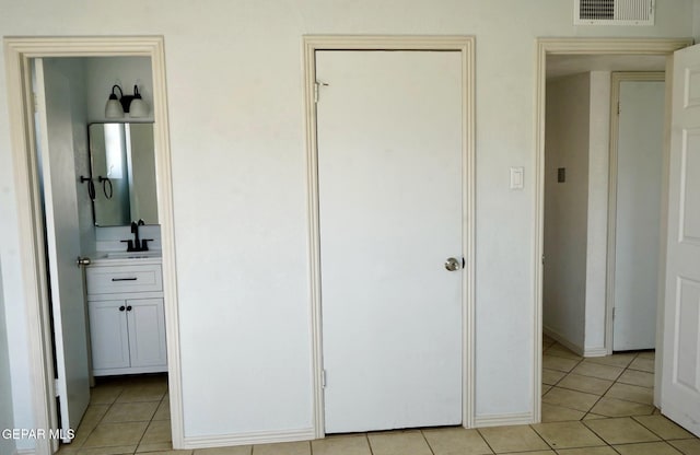 unfurnished bedroom with a sink, visible vents, light tile patterned flooring, and ensuite bath