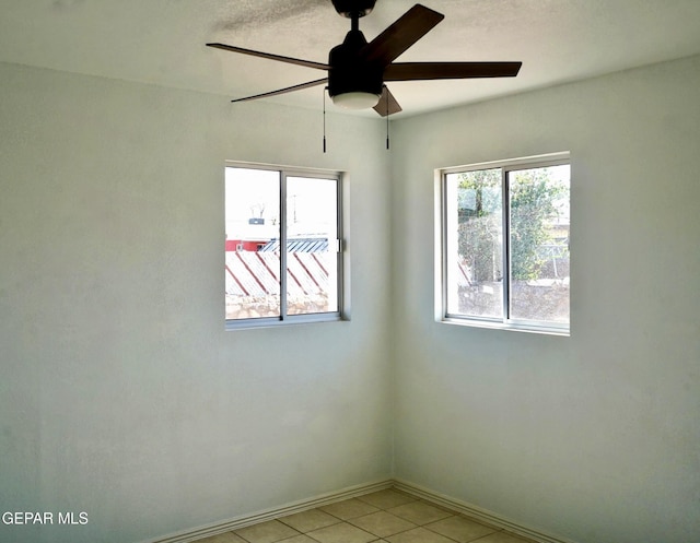 empty room featuring light tile patterned floors, baseboards, and a ceiling fan
