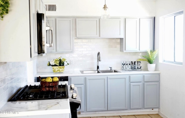 bar with a sink, visible vents, stainless steel microwave, and tasteful backsplash