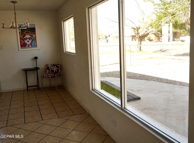 entryway featuring light tile patterned floors, baseboards, and a chandelier